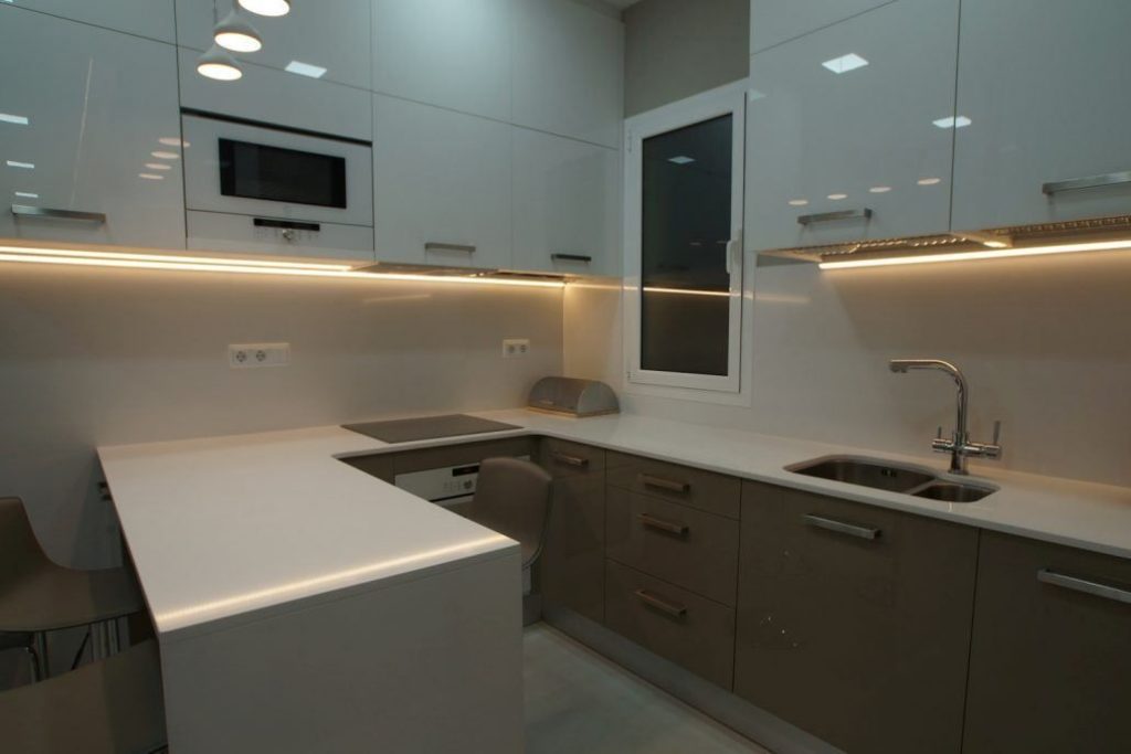 Cocina reformada en el Eixample con muebles claros, campana integrada e iluminación lineal por Lautoka Urbana